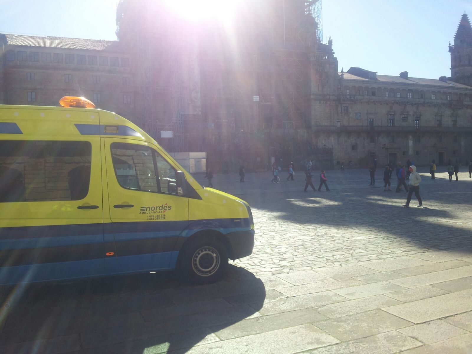 Ambulancia de Ambulancias do Nordés estacionada en la Praza do Obradoiro de Santiago de Compostela en un día soleado